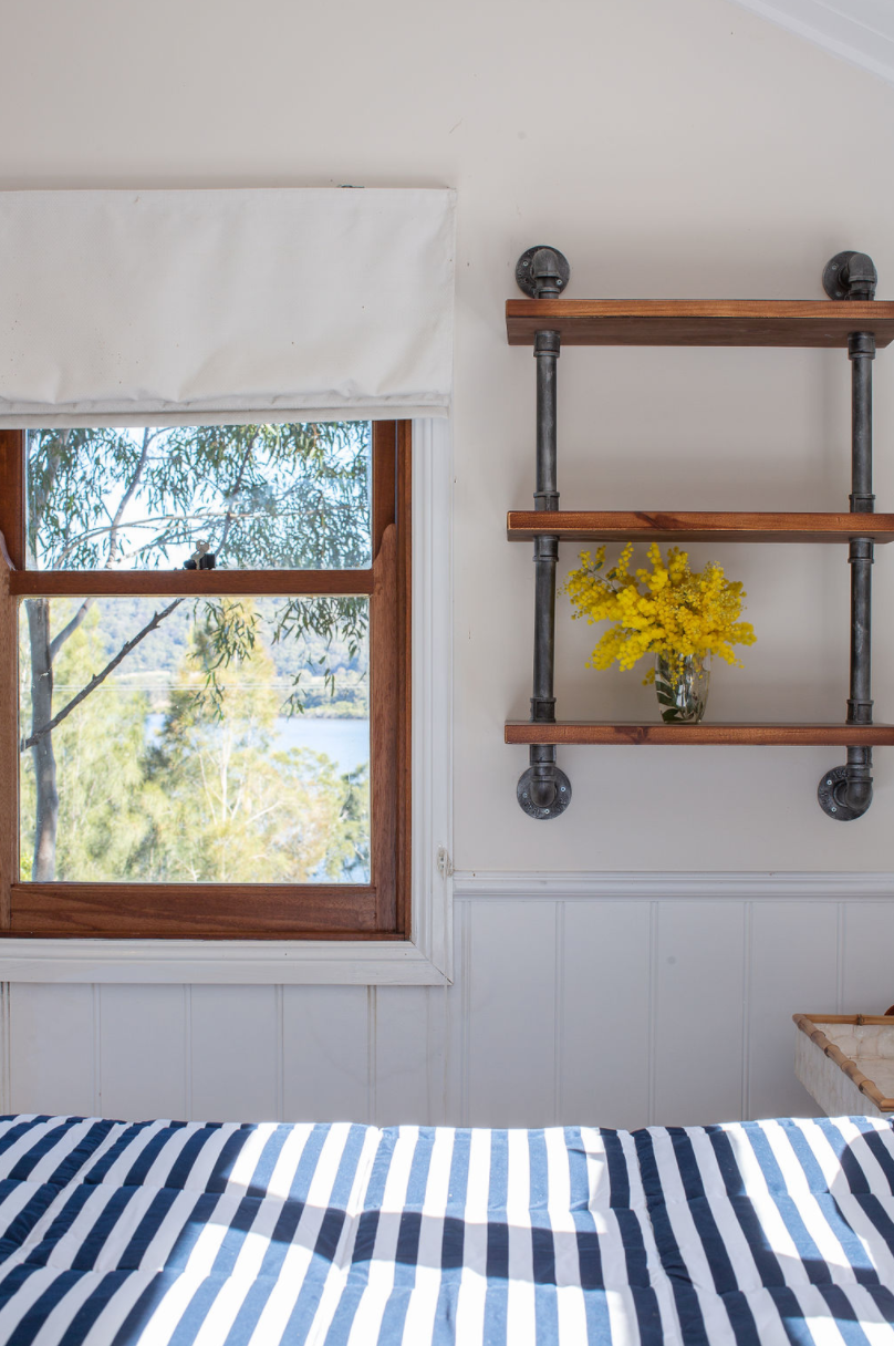 A bedroom with a bed , shelves , and a window.