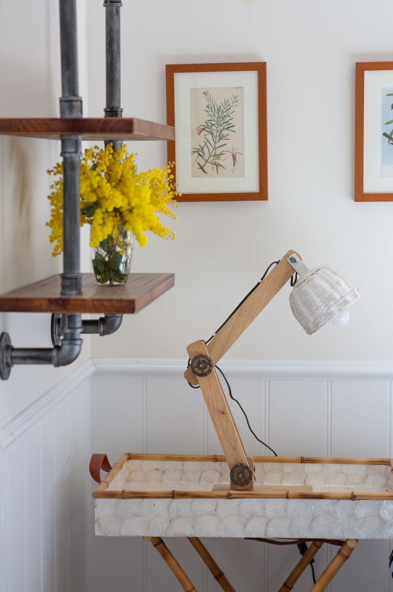 A desk with a lamp and a vase of yellow flowers on it