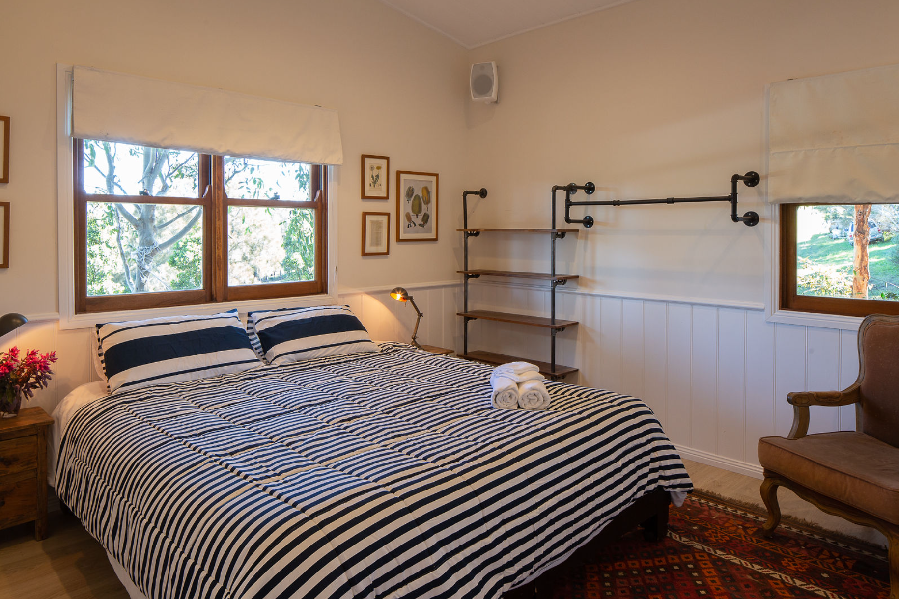 A bedroom with a striped bed and a chair.
