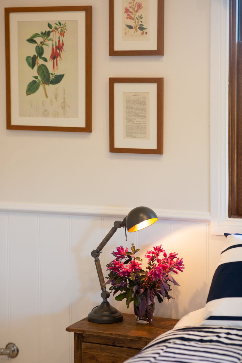 A lamp is sitting on a nightstand next to a bed.