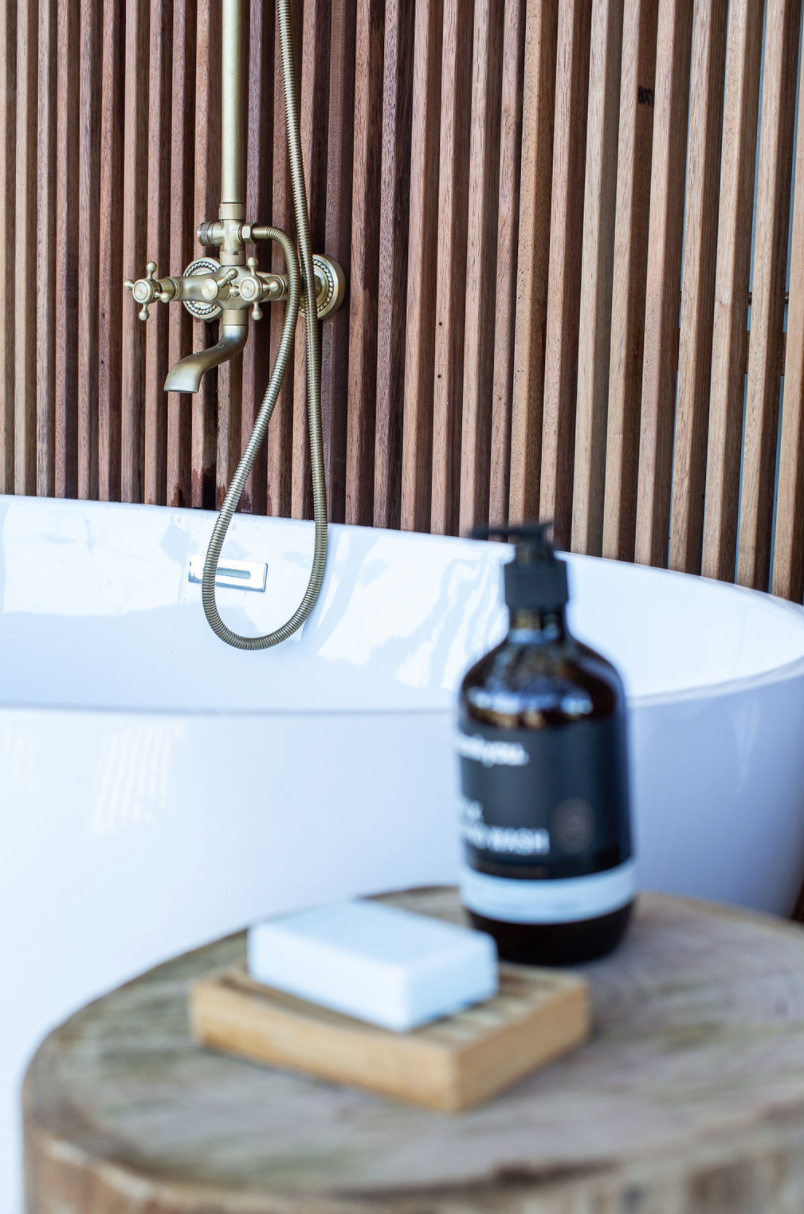 A bathroom with a bathtub and a soap dispenser on a wooden table.
