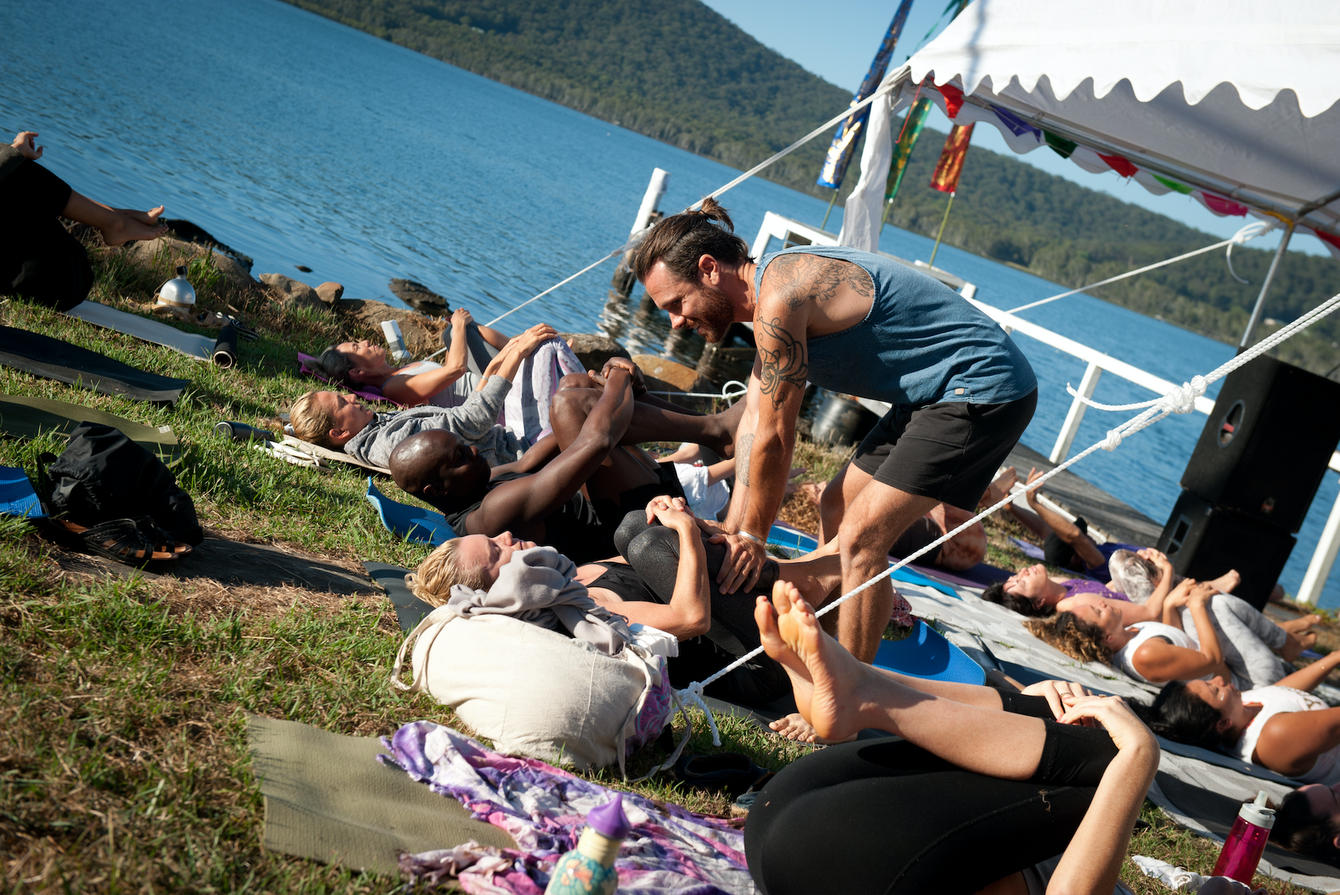A man is helping a group of people do yoga on the beach.