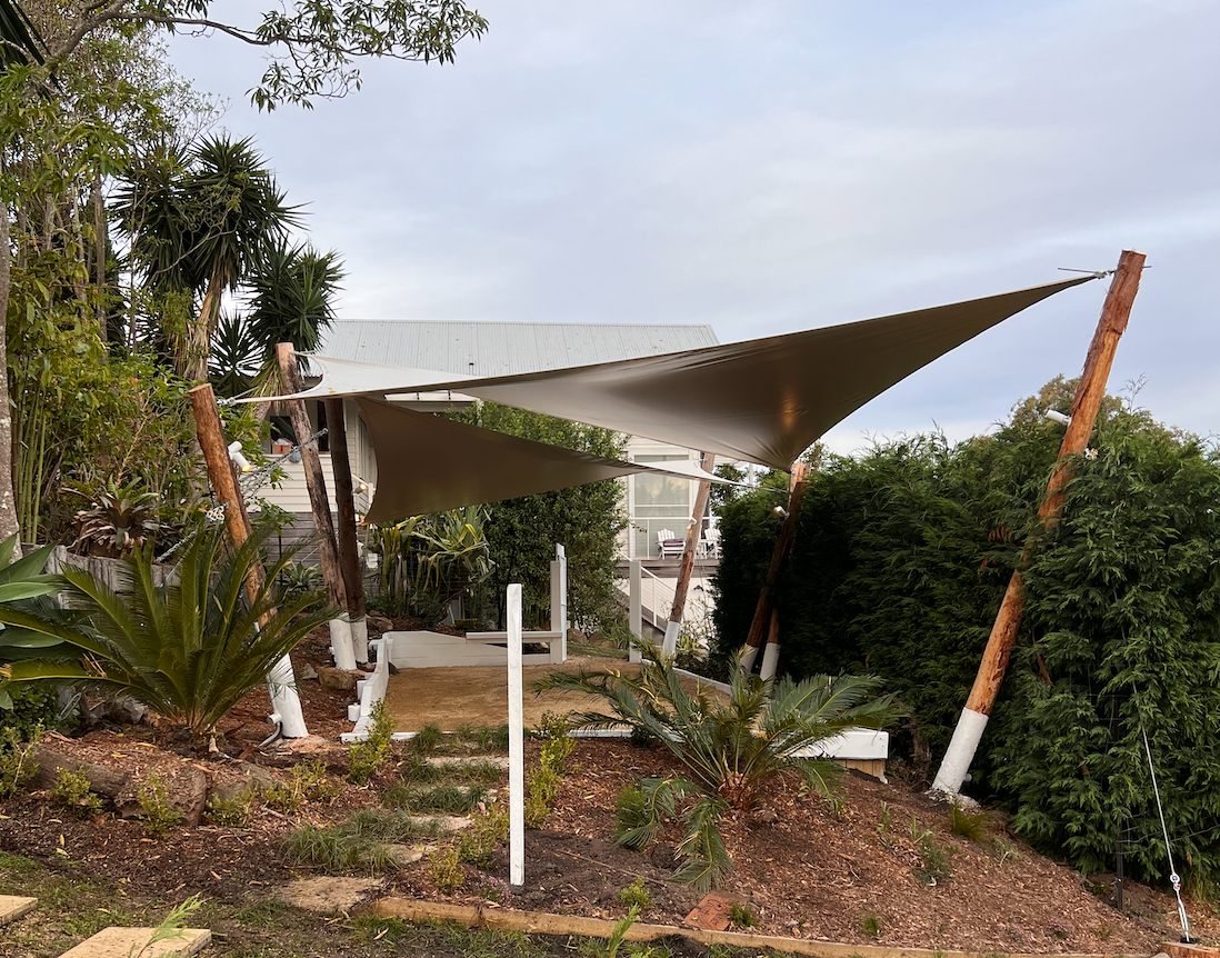 A large white tent is sitting on top of a hill surrounded by trees.