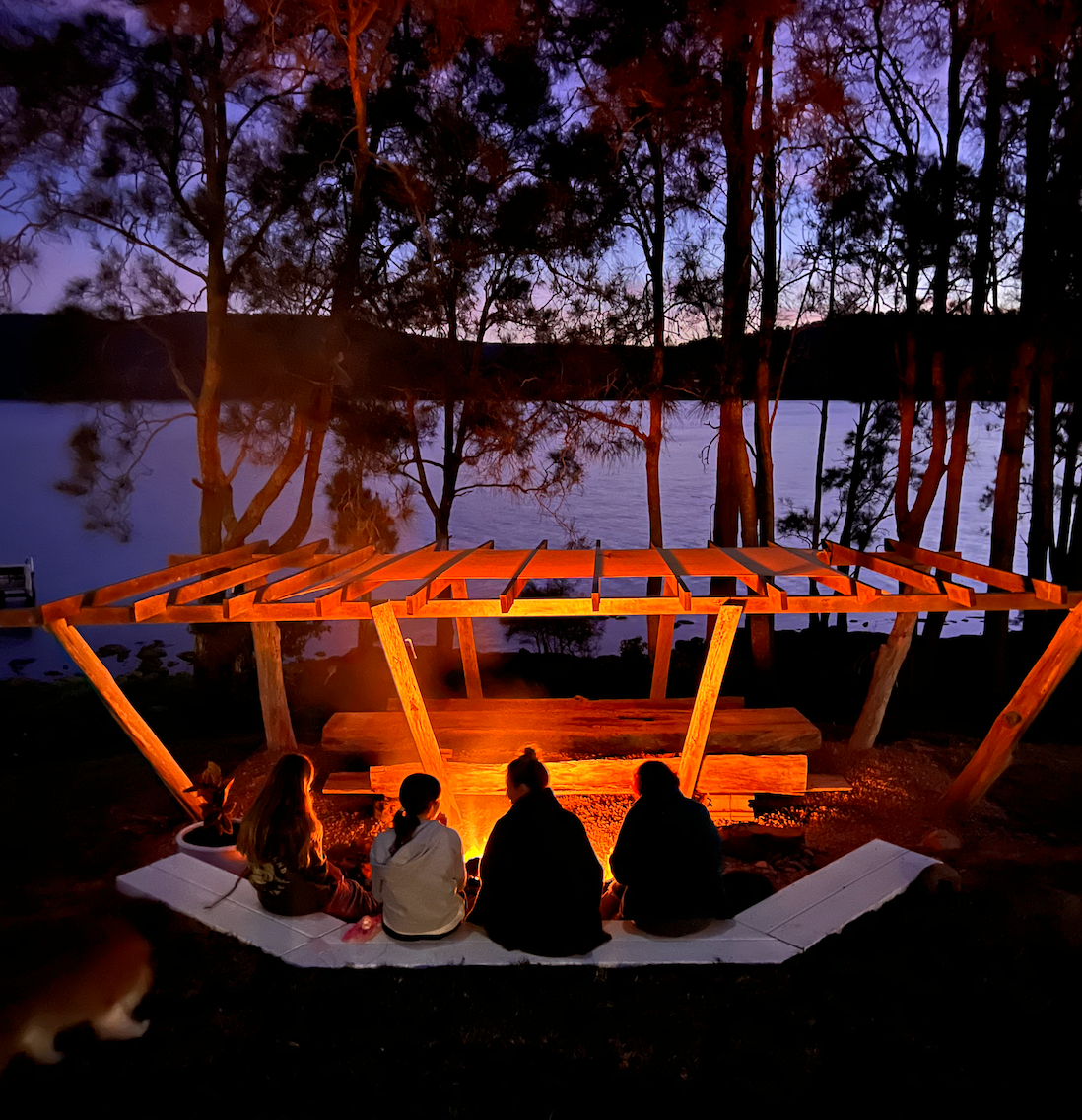 A group of people are sitting around a fire in the woods