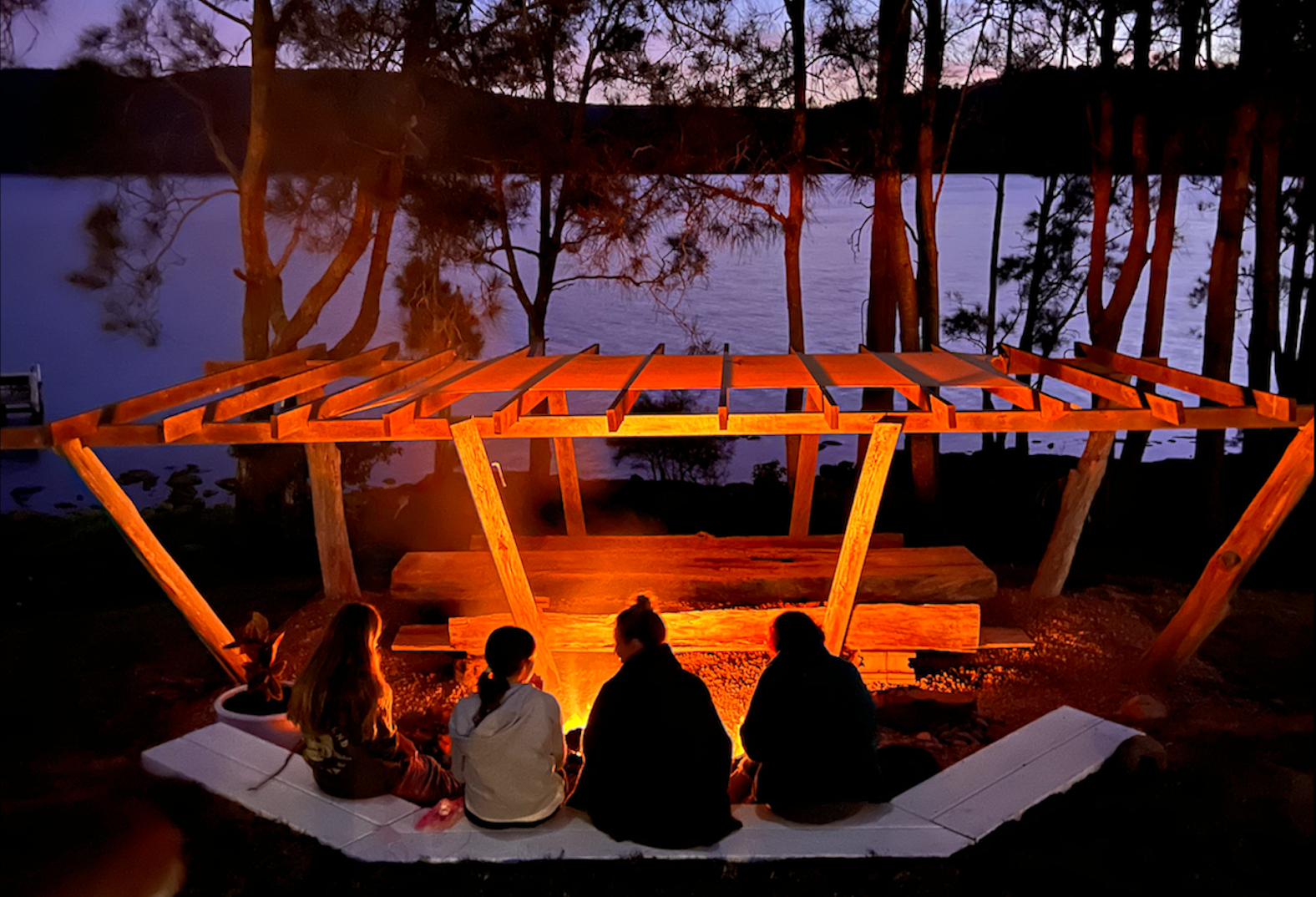 A group of people are sitting around a fire in the woods