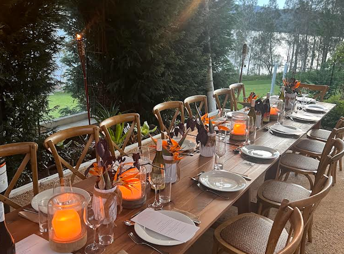 A long wooden table with plates , glasses , and candles on it.