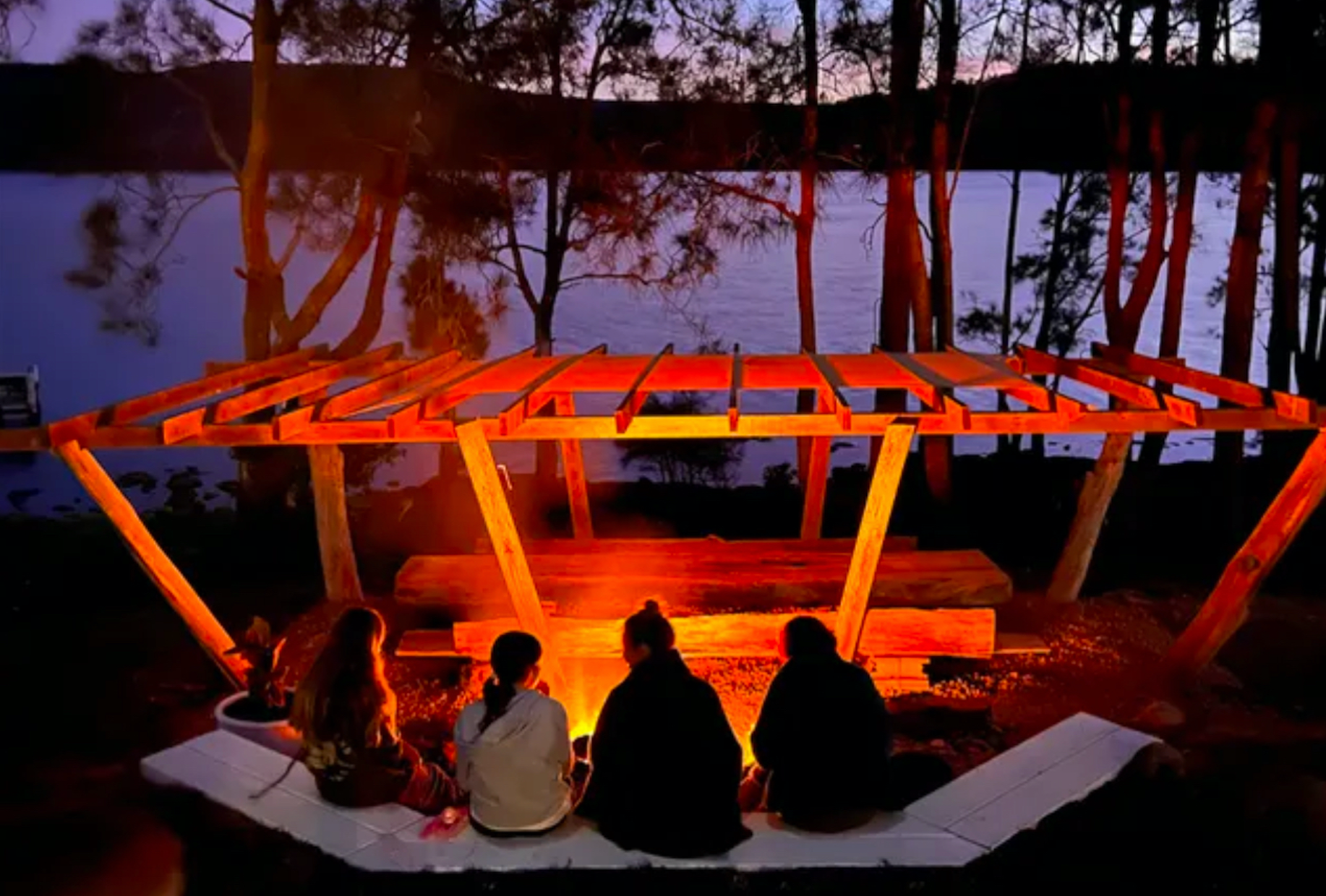 A group of people are sitting around a fire in the woods