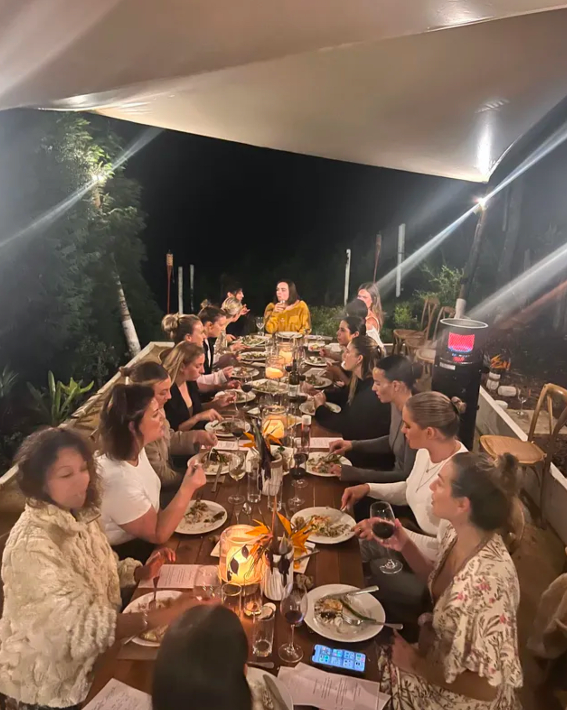 A group of people are sitting at a long table eating food.