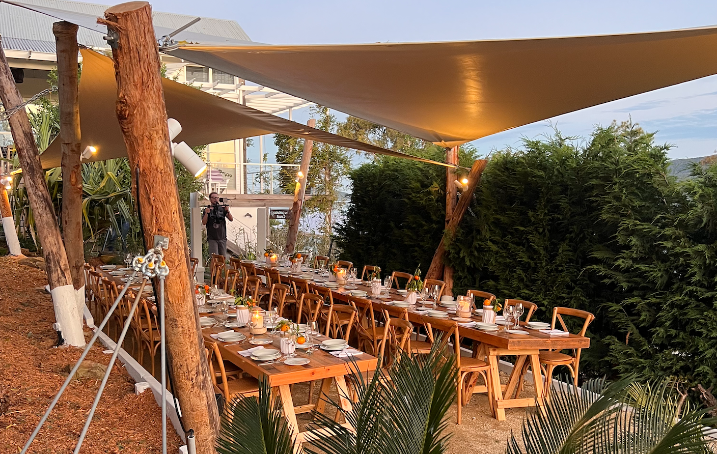 A long table and chairs under a canopy.