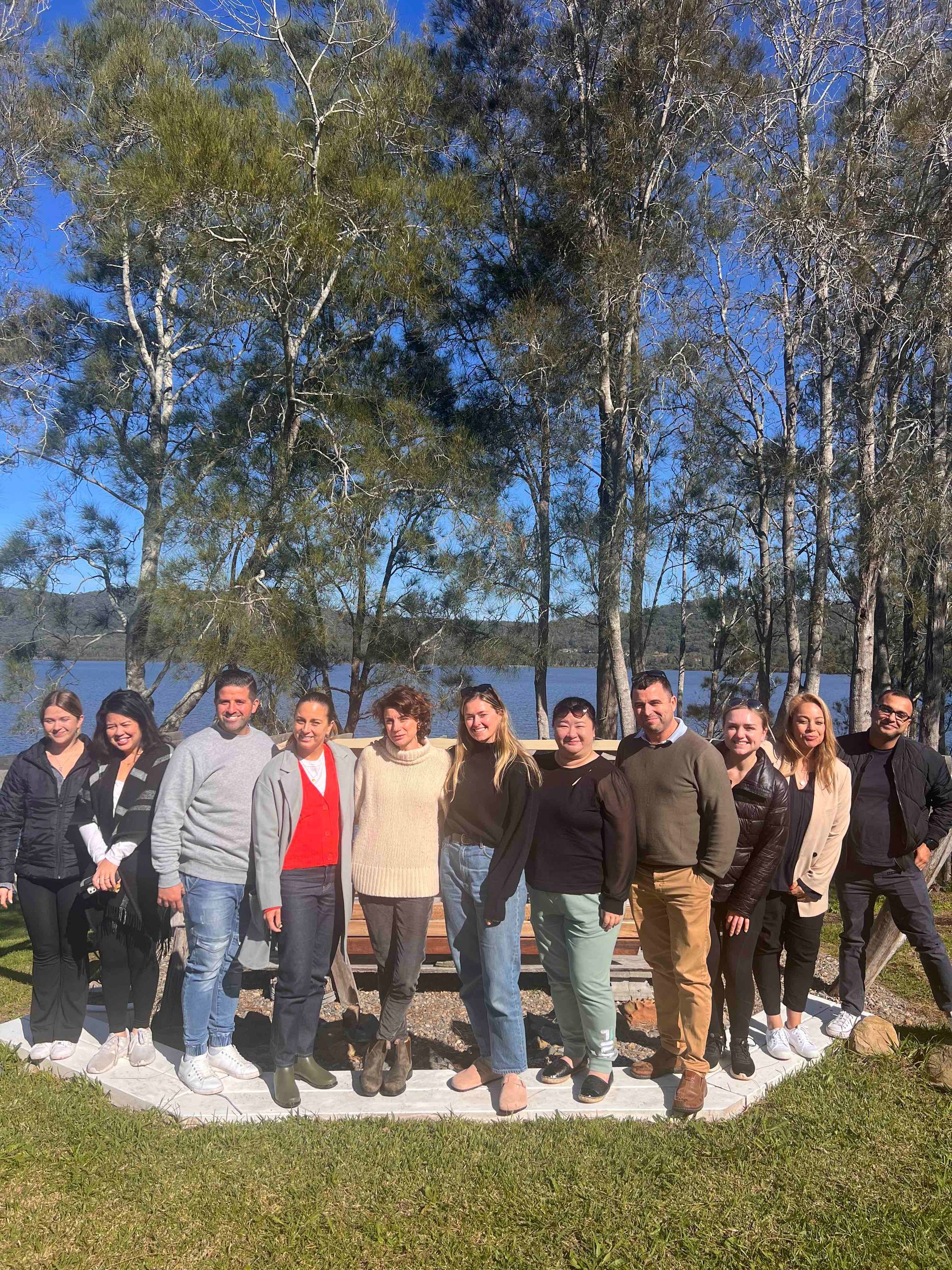 A group of people are posing for a picture in front of a lake.