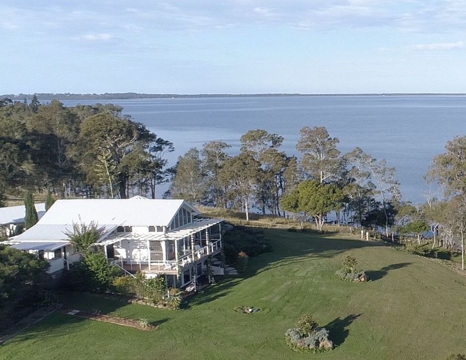An aerial view of a house next to a body of water