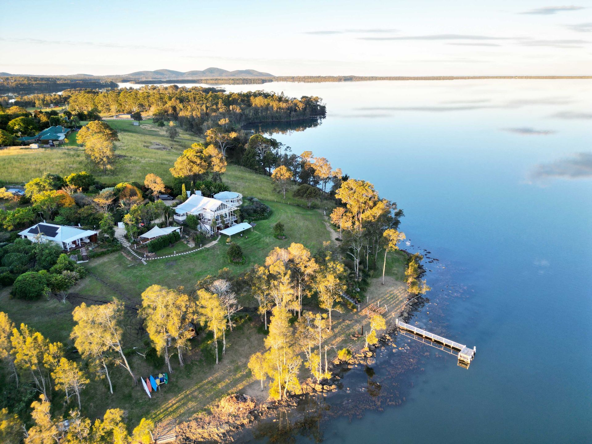 An aerial view of a lake with a house on the shore