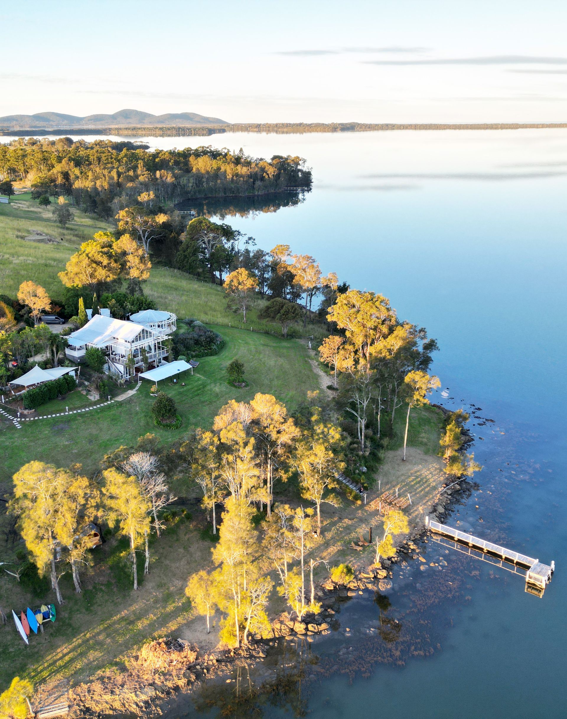 An aerial view of a large body of water with a house on the shore.