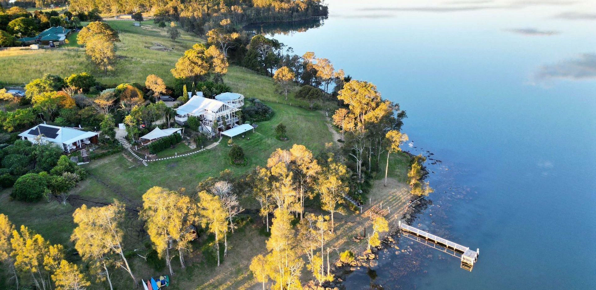 An aerial view of a lake with a dock and a house on the shore.