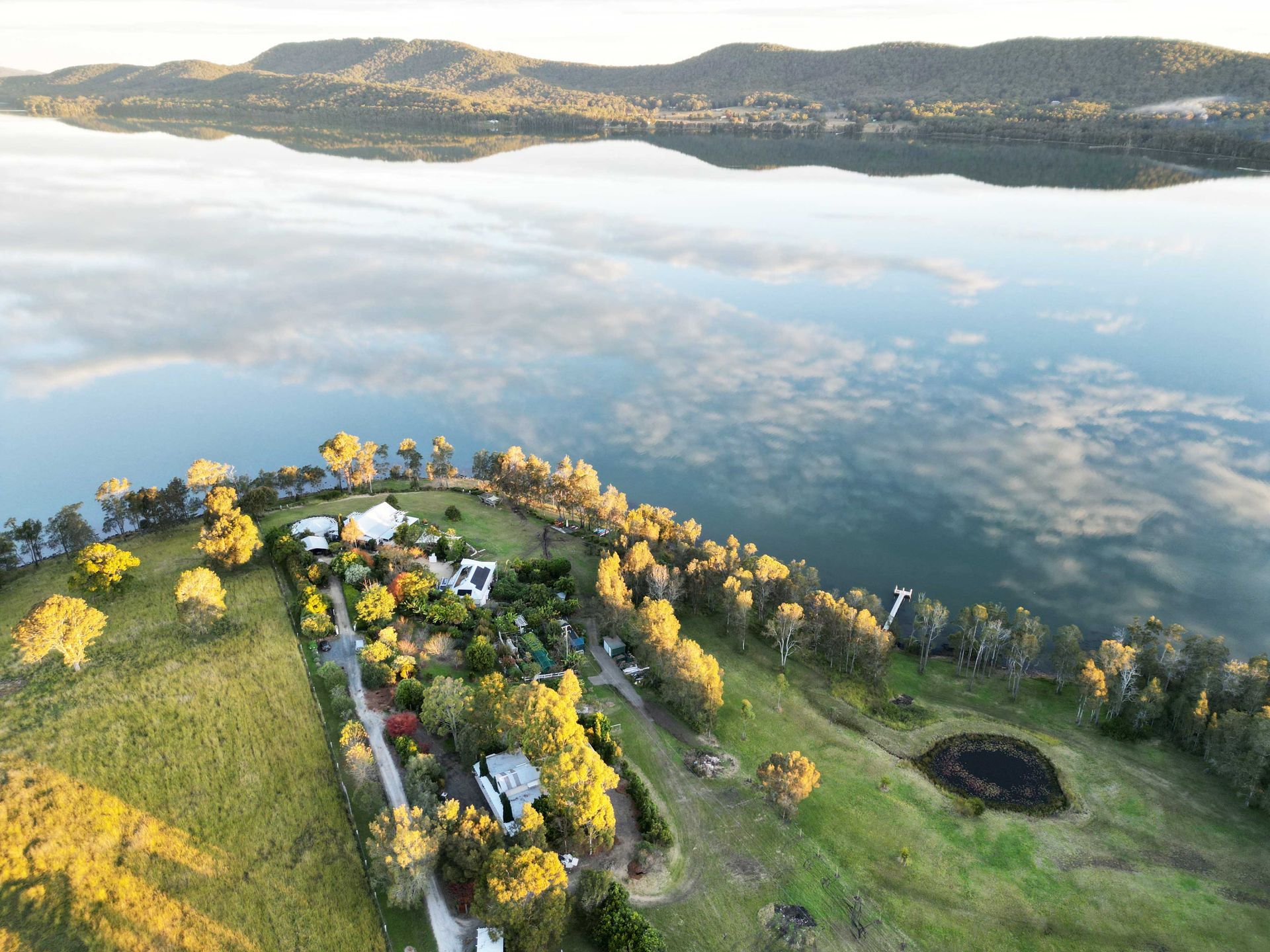 An aerial view of a lake with a house on the shore.