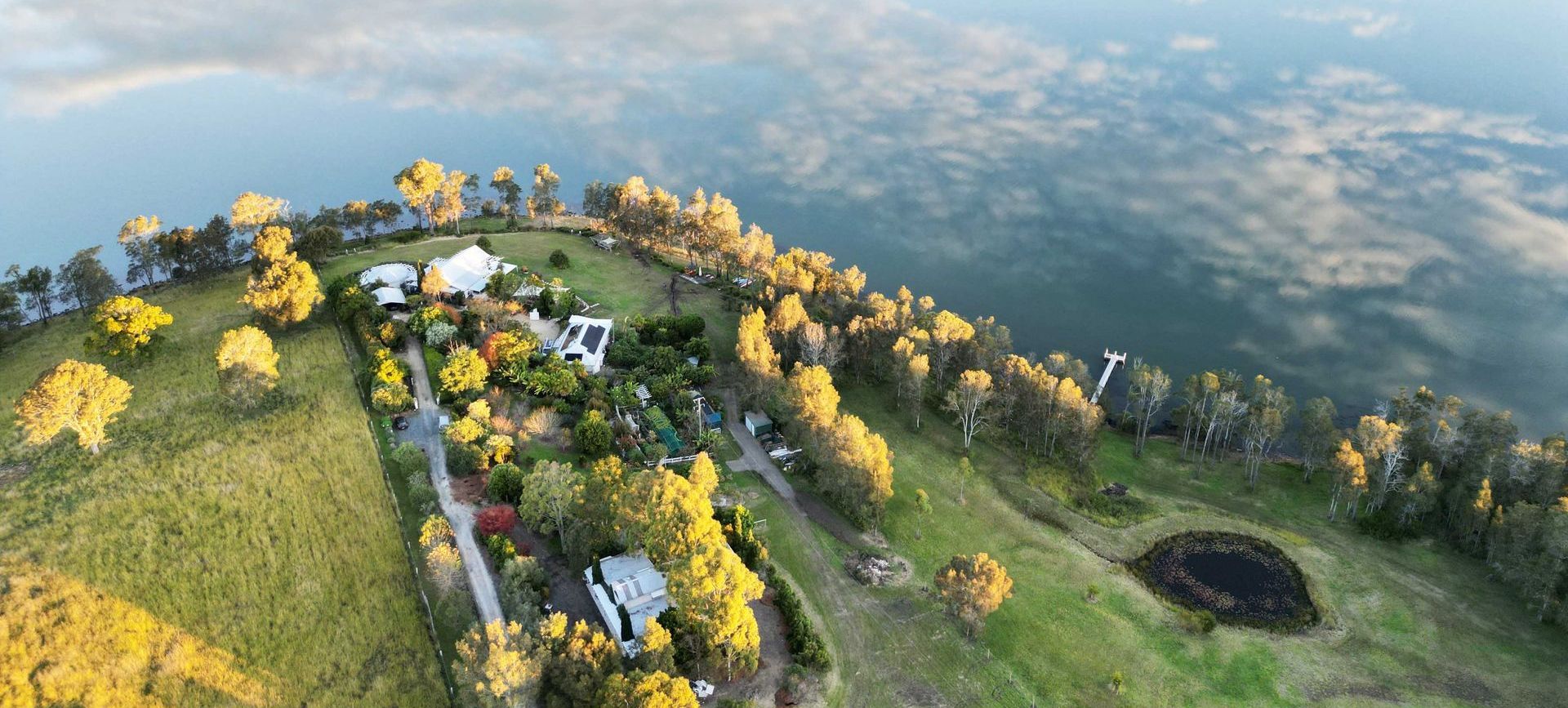 An aerial view of a lush green hillside surrounded by trees and a lake.