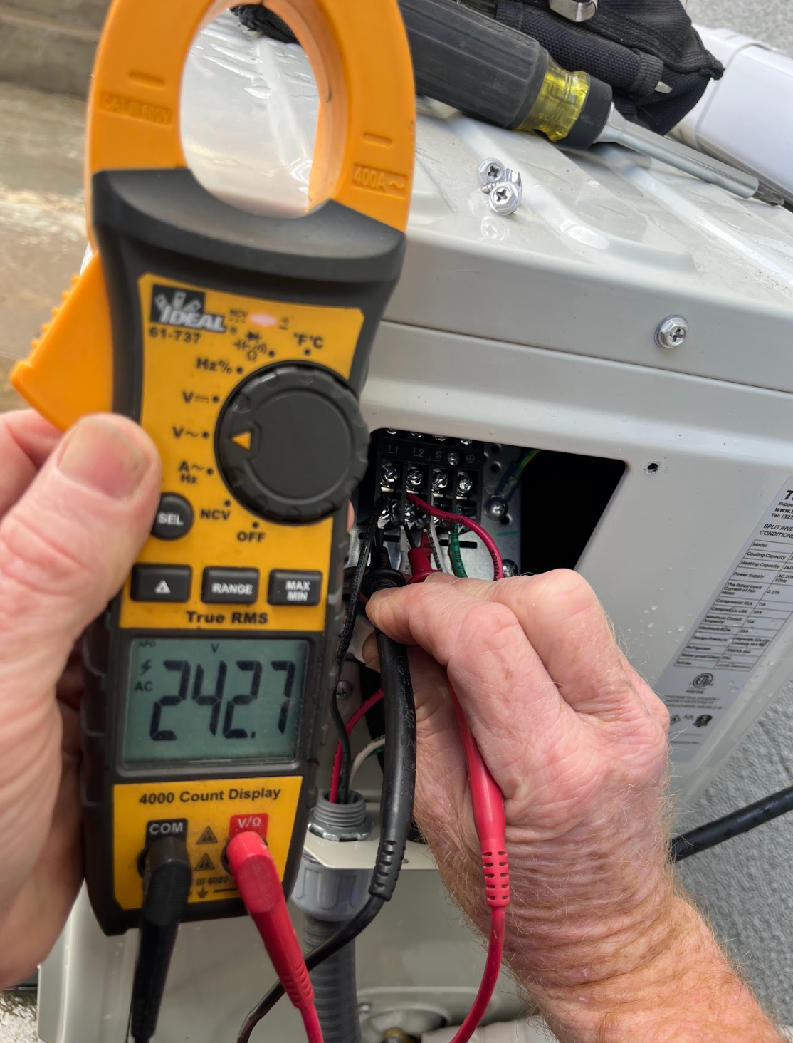 Two workers install a rectangular solar panel onto a metal mounting frame on a rooftop.