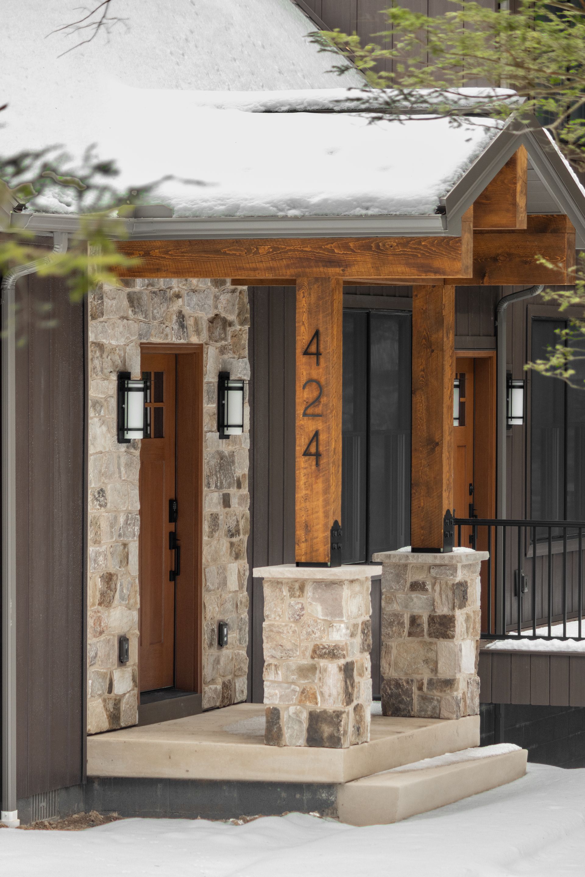 Modern stone and wood house entrance with a covered porch and house number 4244