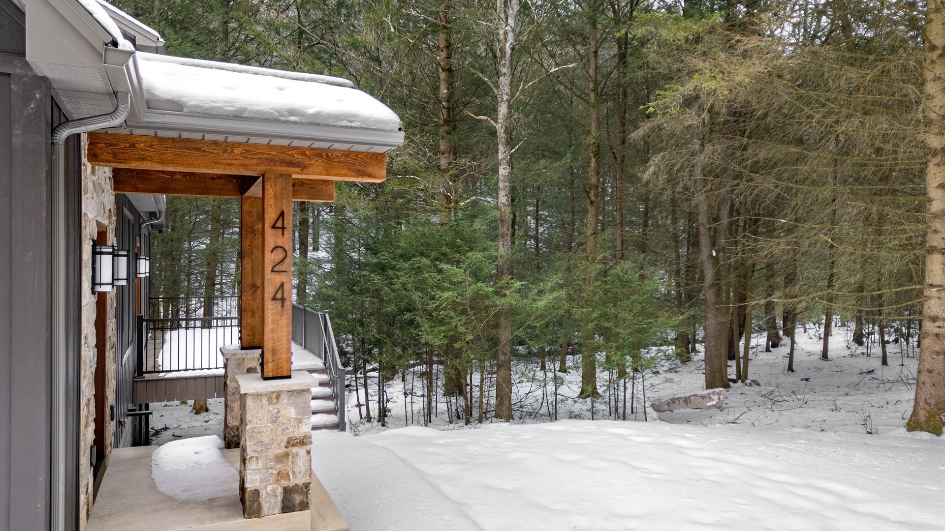 Snow-covered cabin porch beside a wooded forest in winter