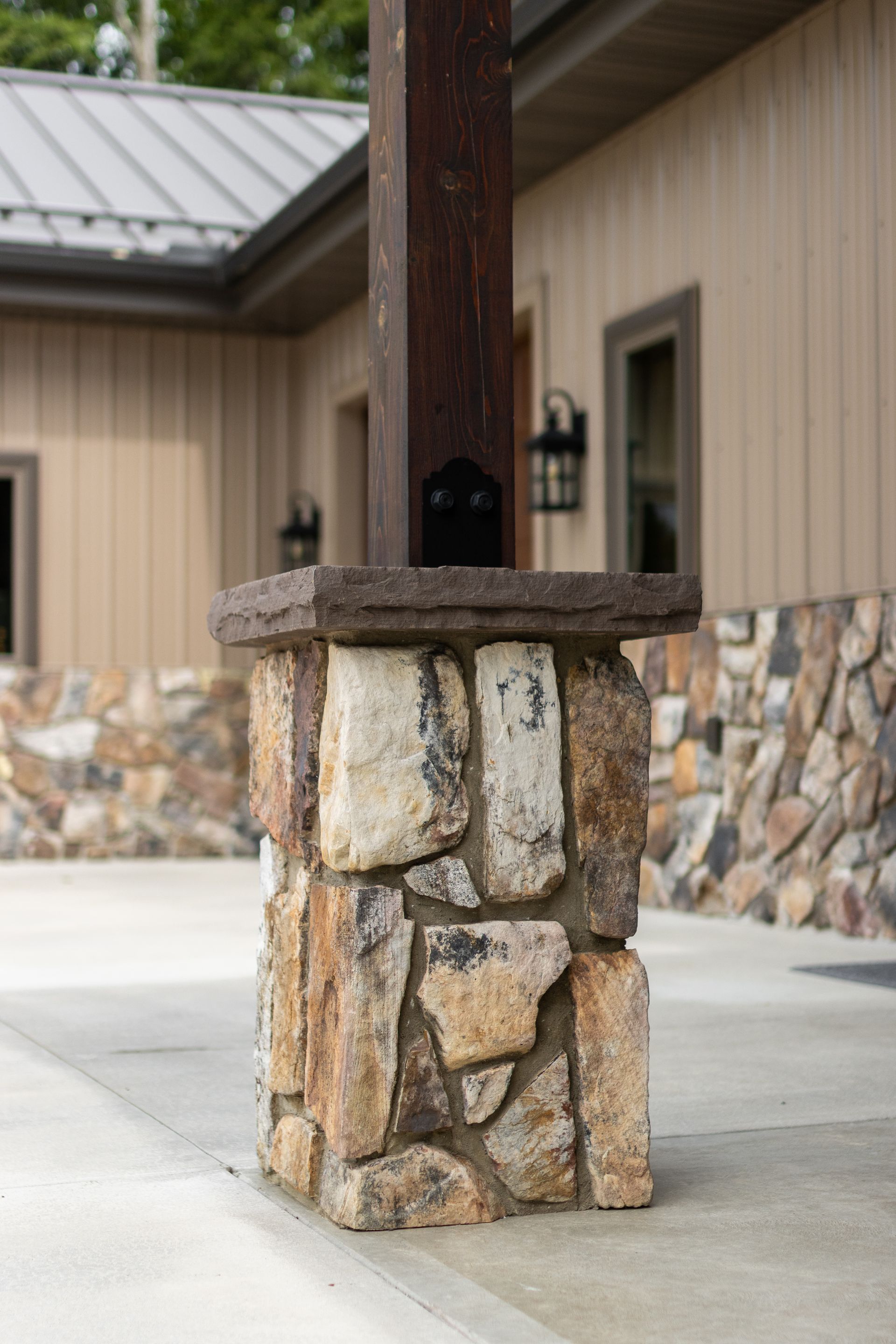 Stone-and-wood column supporting a roofed entrance outside a tan building