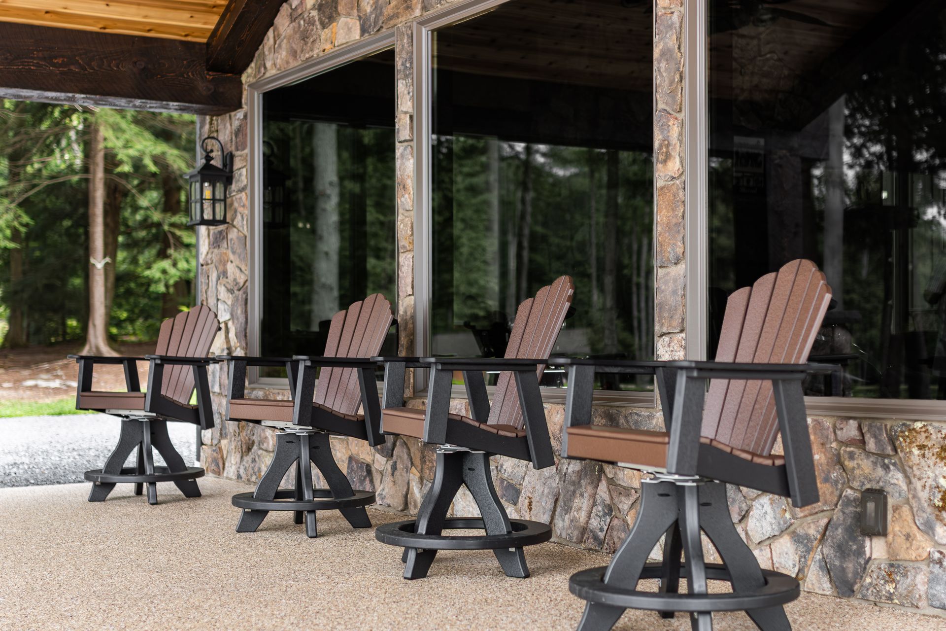 Four wooden chairs on a covered stone porch beside large dark-tinted windows
