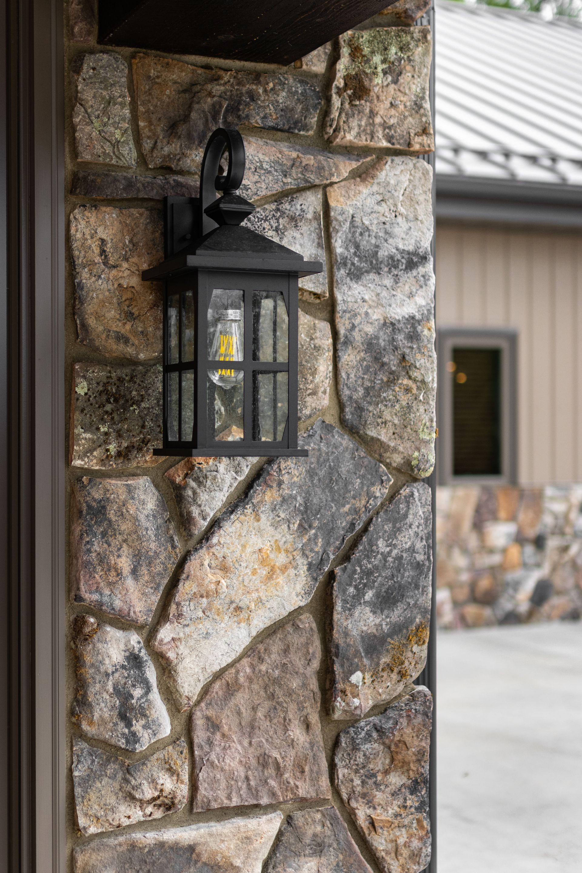 Black lantern mounted on a stone pillar beside a building entrance.