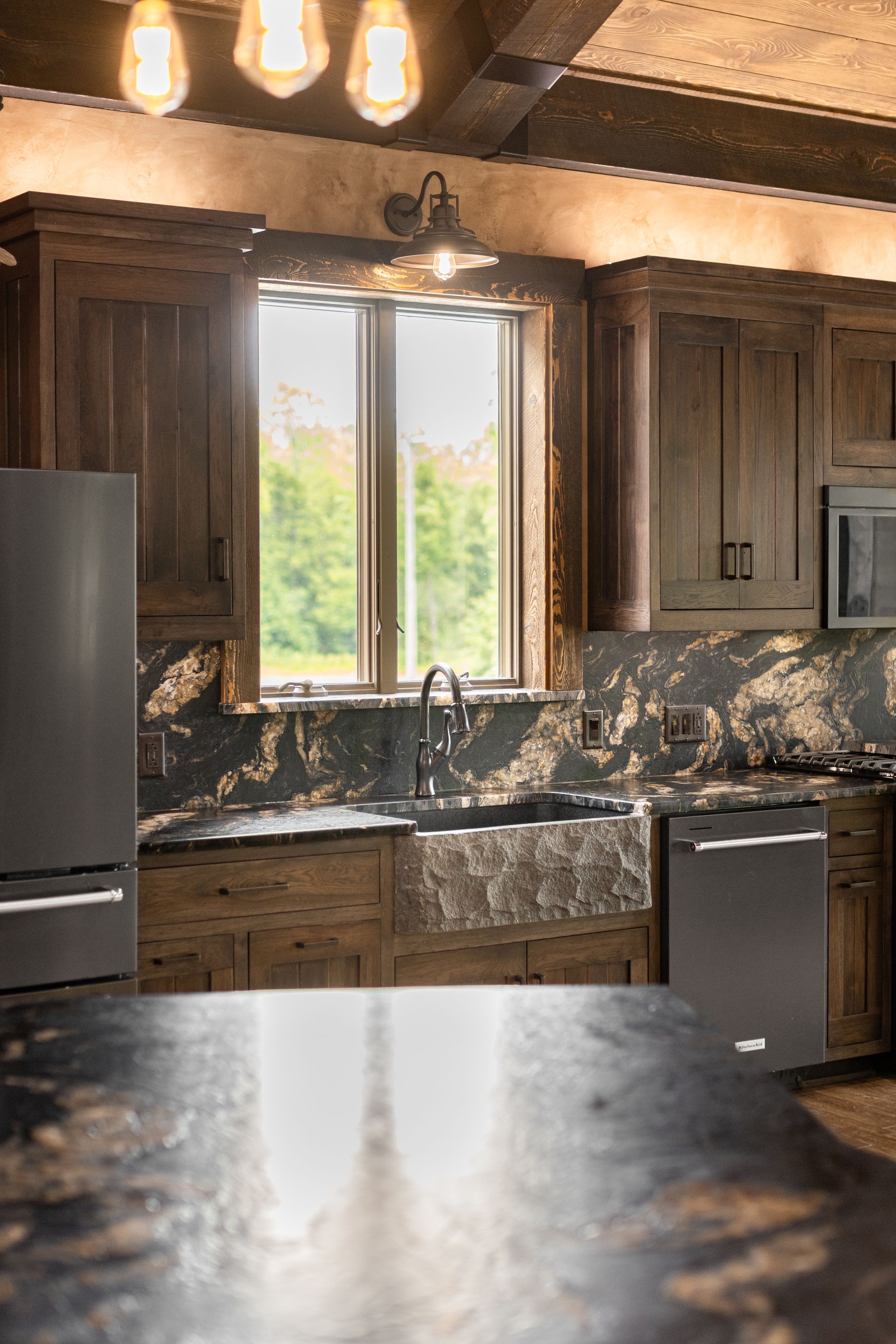 Rustic kitchen with dark wood cabinets, granite counters, and a bright window over the sink