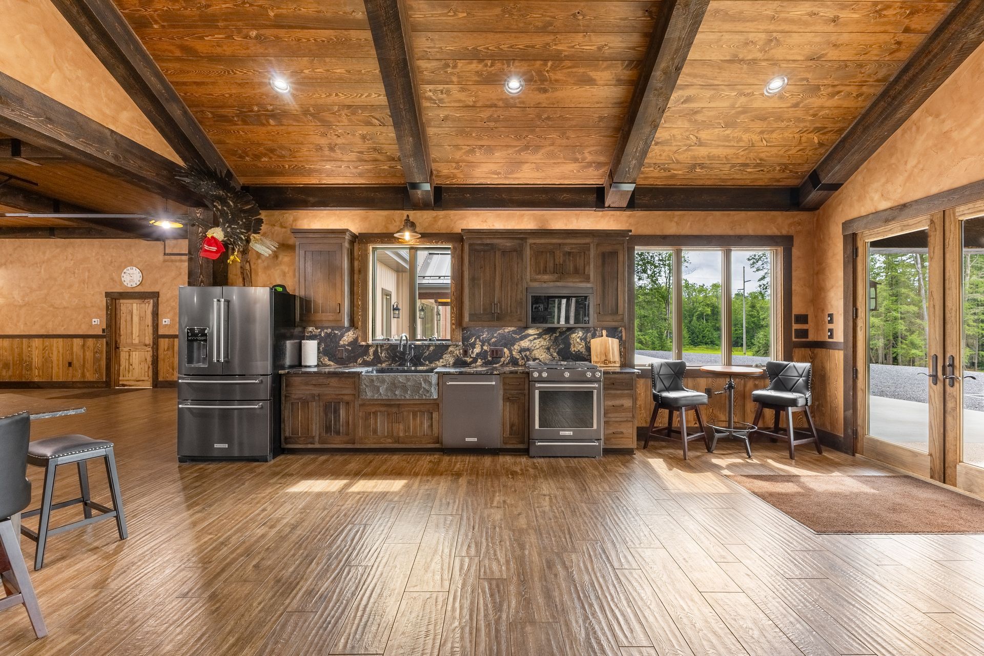 Spacious rustic kitchen with wood ceiling, large windows, and stainless steel appliances