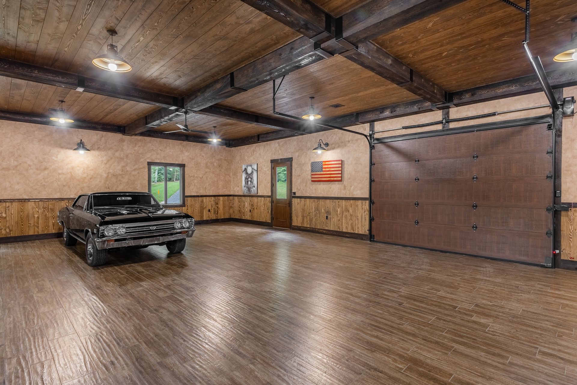 Spacious garage with a black car, wood-paneled walls, and a large brown overhead door.