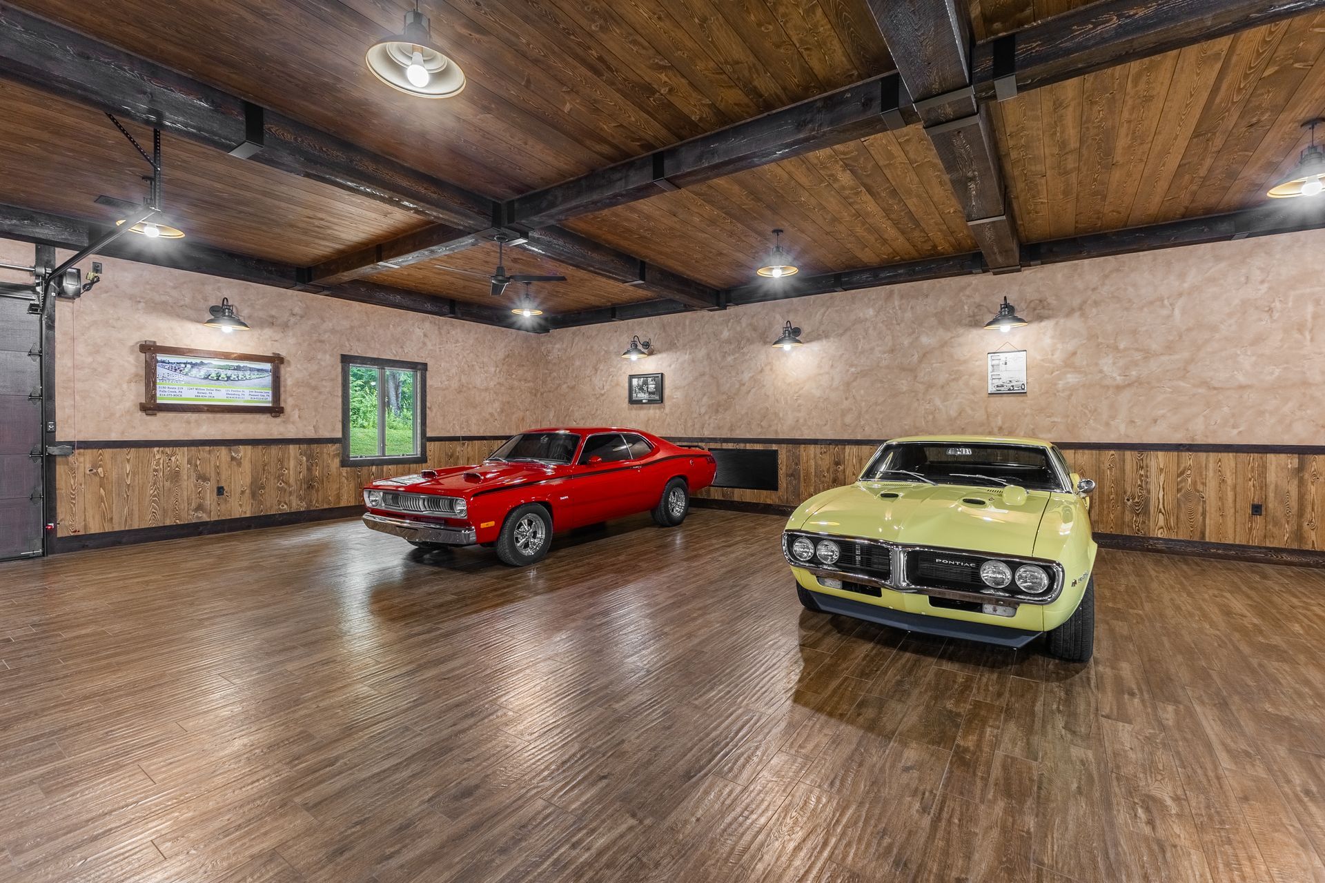 Two classic cars in a wood-paneled garage, one red and one yellow under ceiling lights.