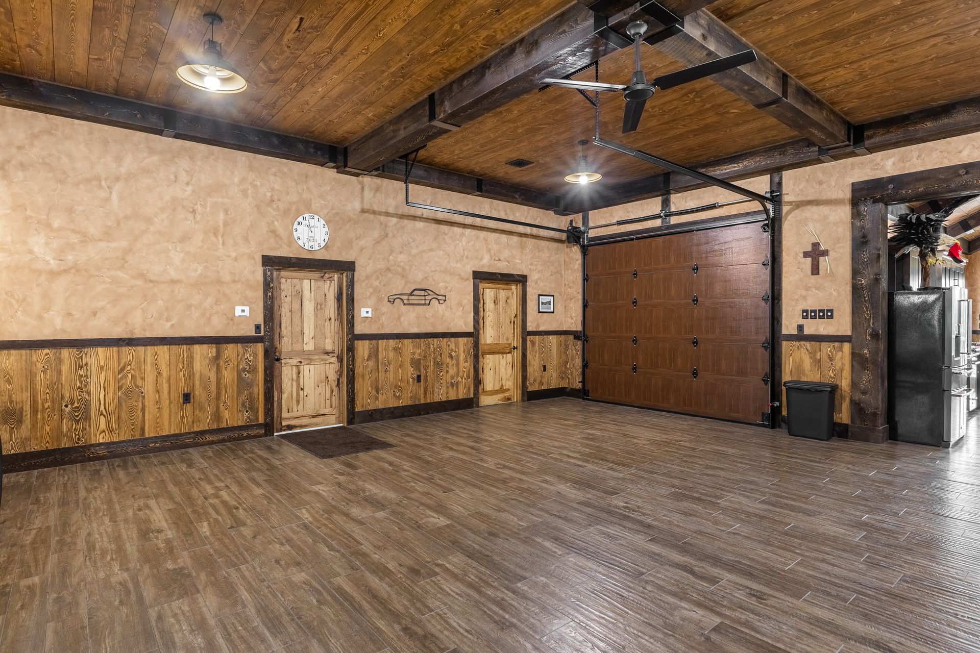 Empty rustic room with wood floor, paneled walls, and exposed ceiling beams