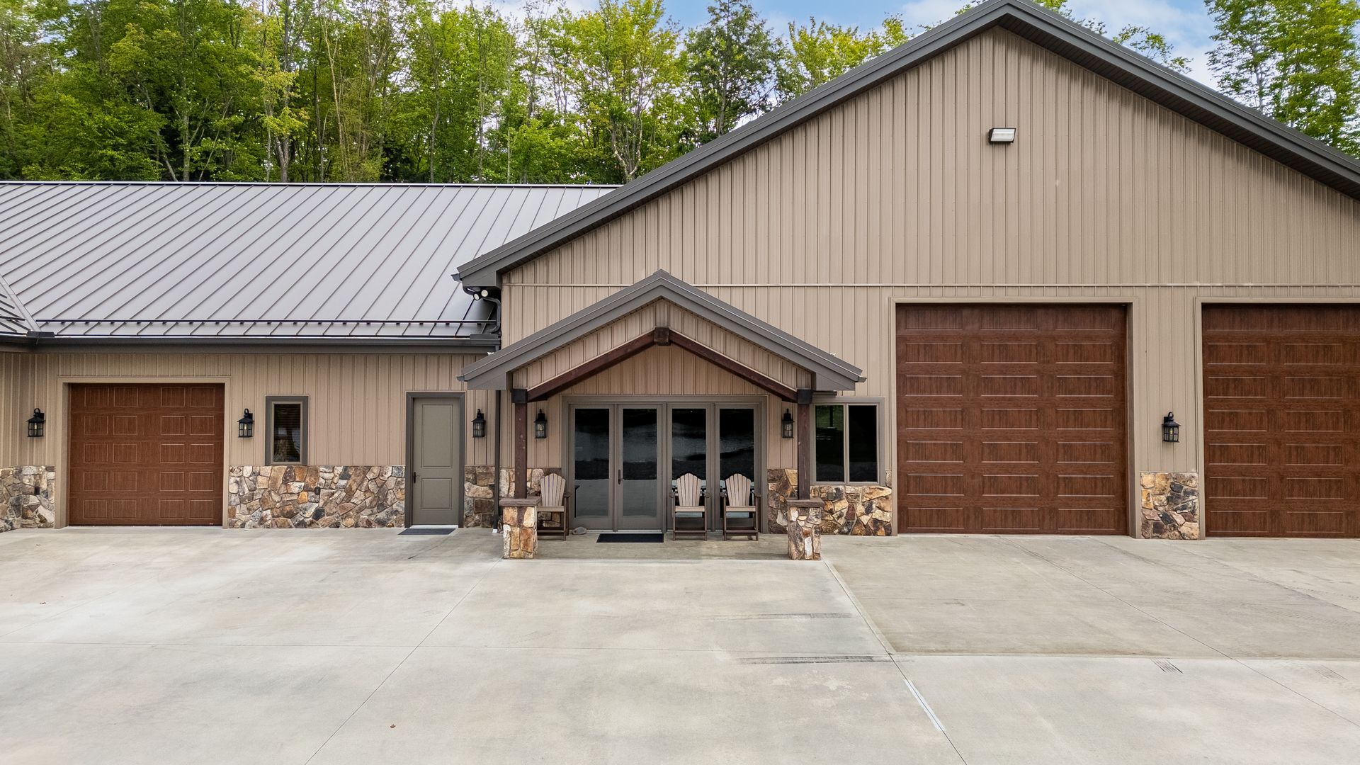 Tan garage building with two roll-up doors, small porch, and bicycles parked outside