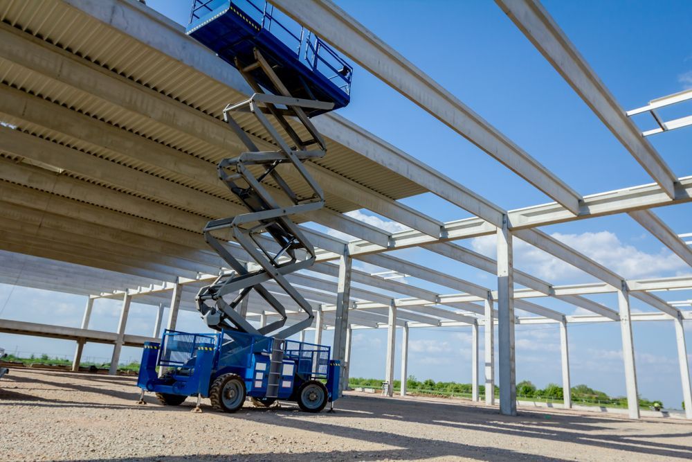 A Blue Scissor Lift Is Sitting on Top of A Building Under Construction — PEPS Machinery Services In Gold Coast, QLD