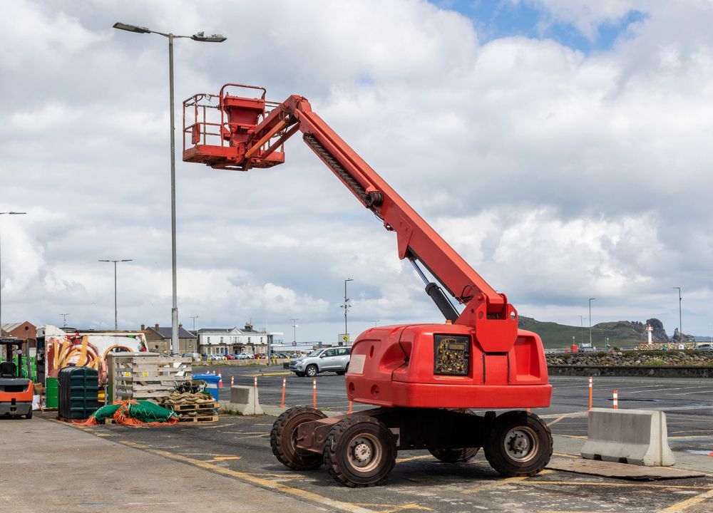 A Red Aerial Lift Is Parked in A Parking Lot — PEPS Machinery Services In Ipswich, QLD
