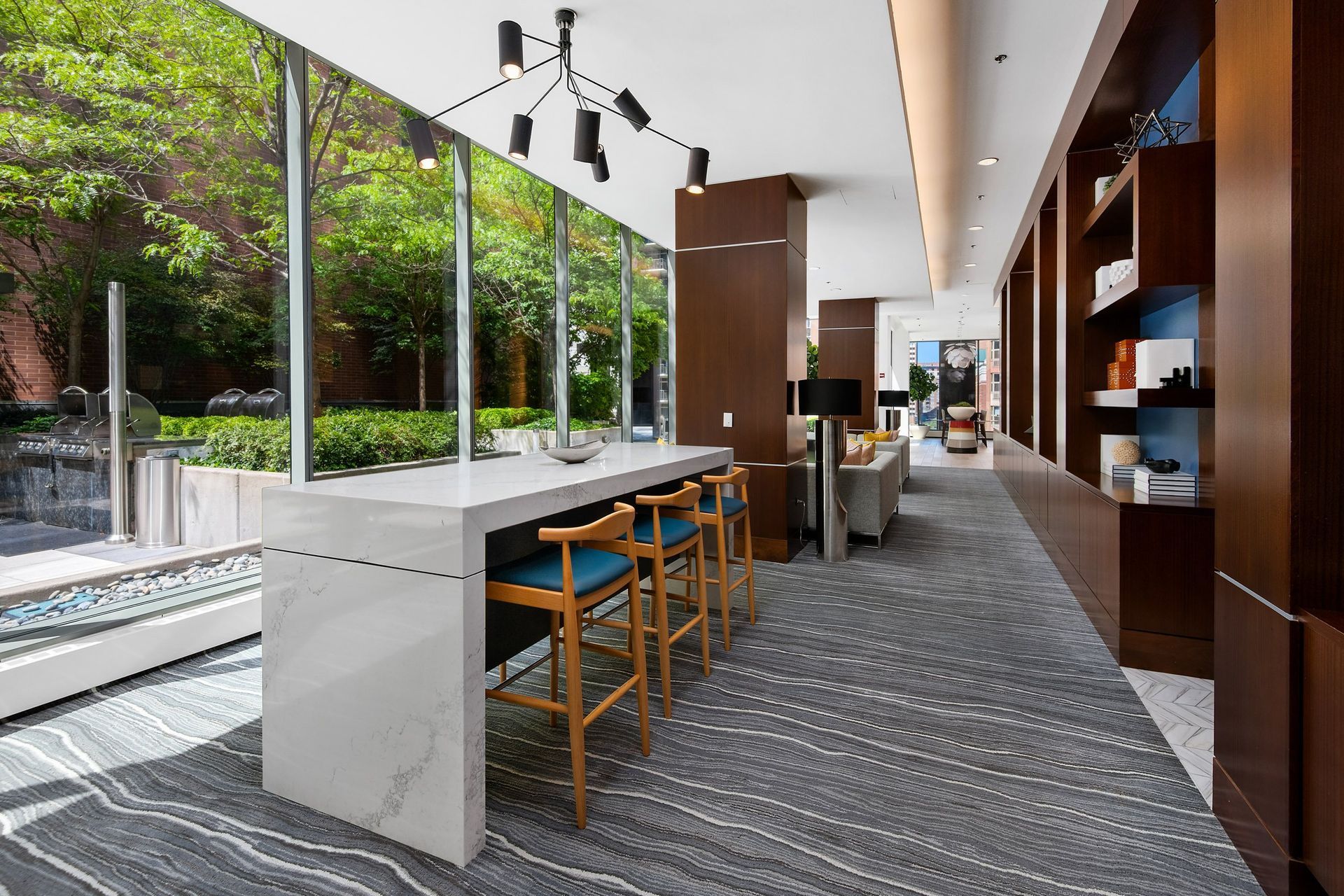 a long kitchen with a long counter and chairs in front of a window