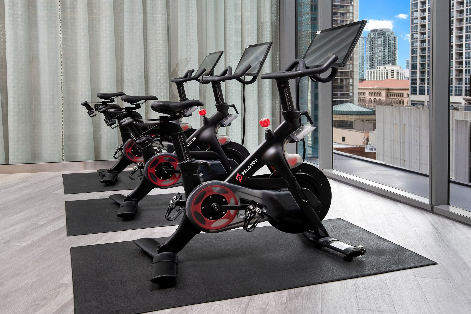 a row of spin bikes in a gym in front of a window