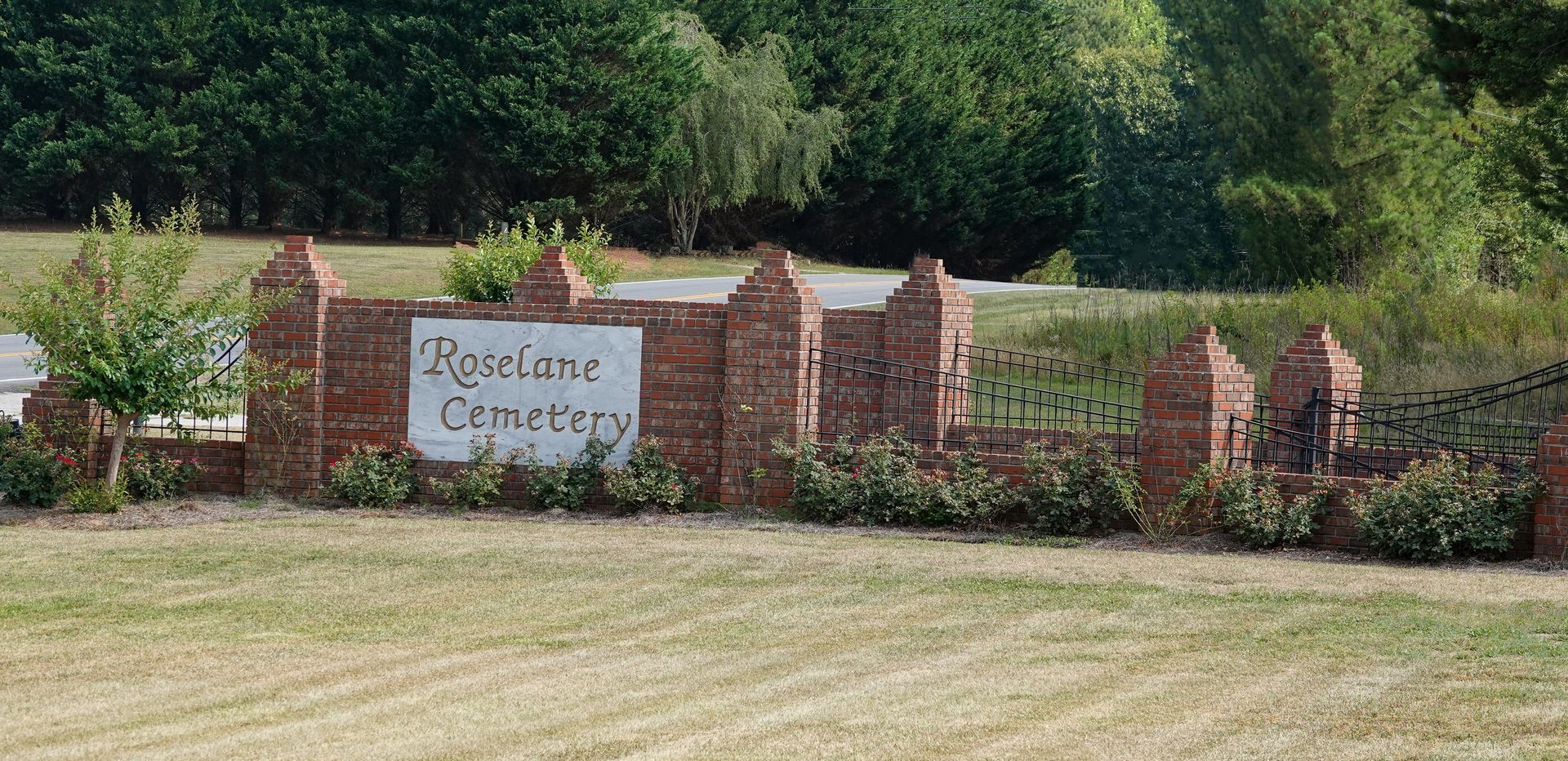 Brick entrance sign reading “Mooring Centre” beside a hedge and trees