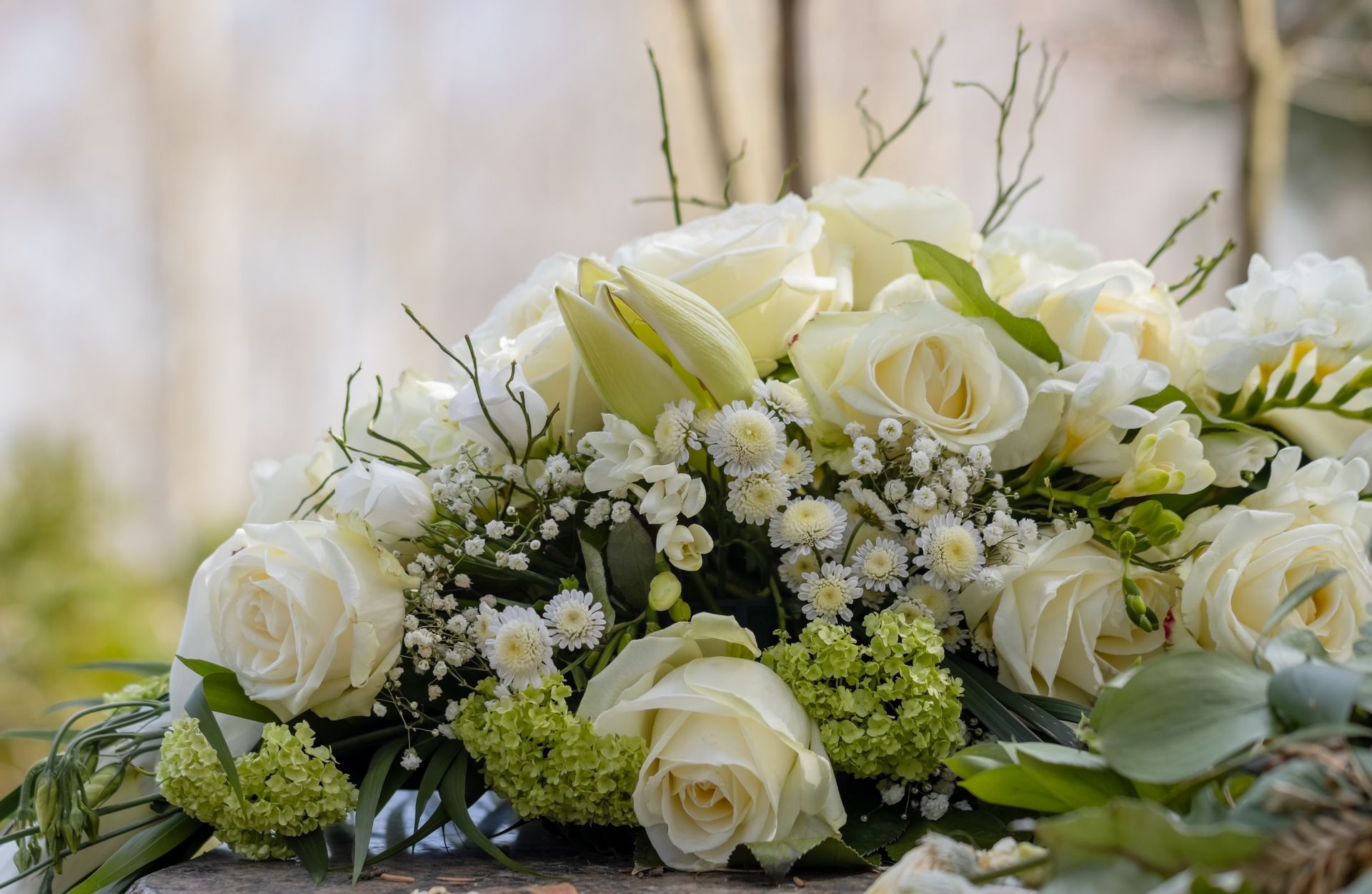 White roses and baby's breath arranged in a floral centerpiece with greenery