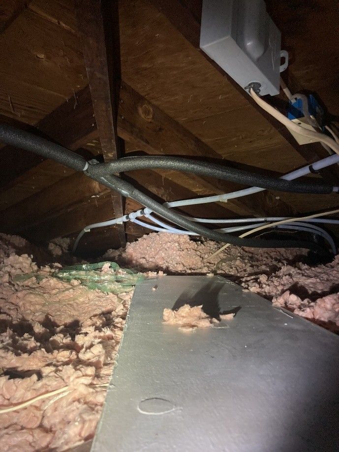 Attic view with insulation, electrical wires, and a metal plate. Attic view with insulation, electrical wires, and a metal plate.