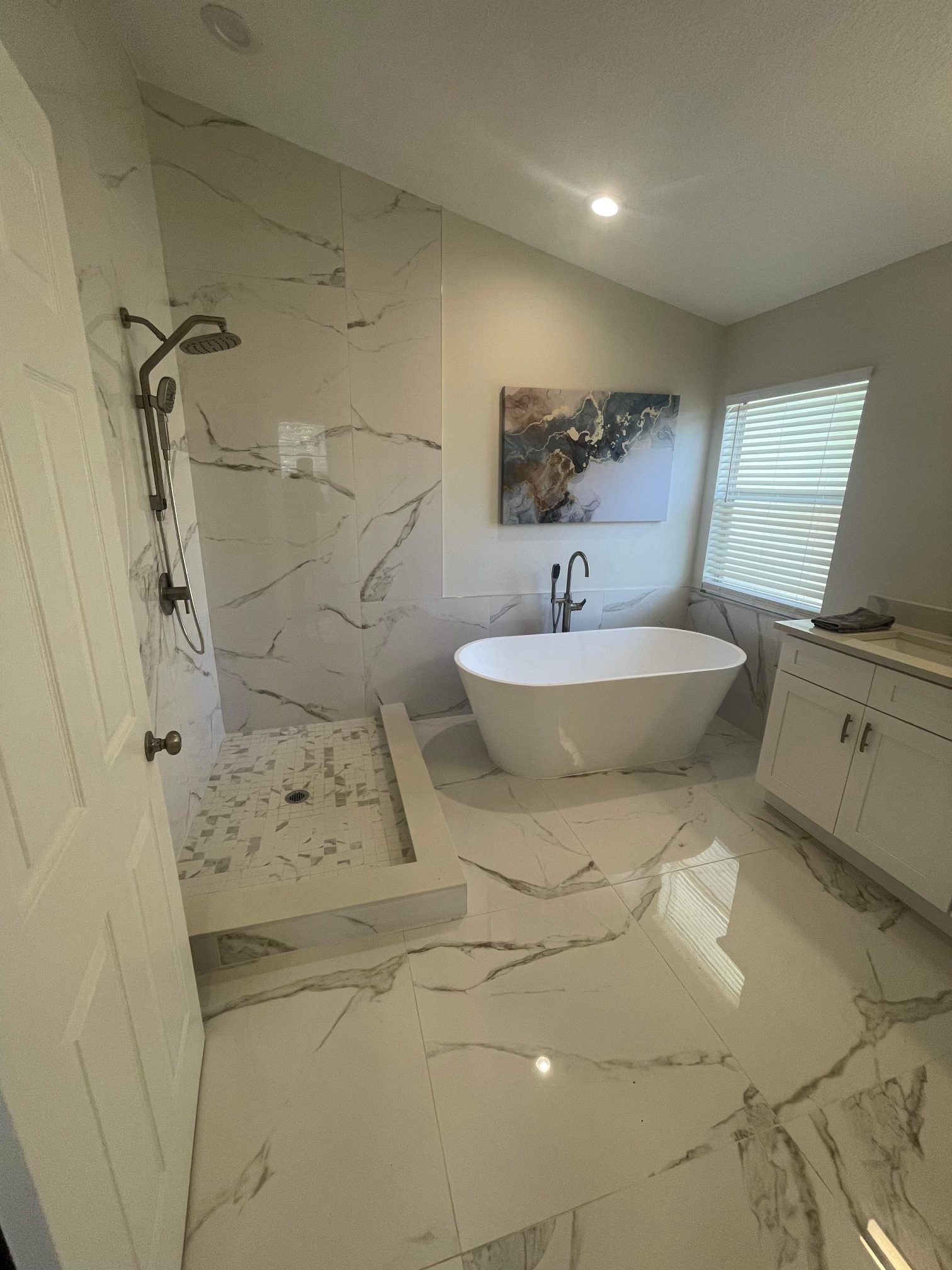 Bathroom with marble-look tile, walk-in shower, freestanding tub, and vanity.