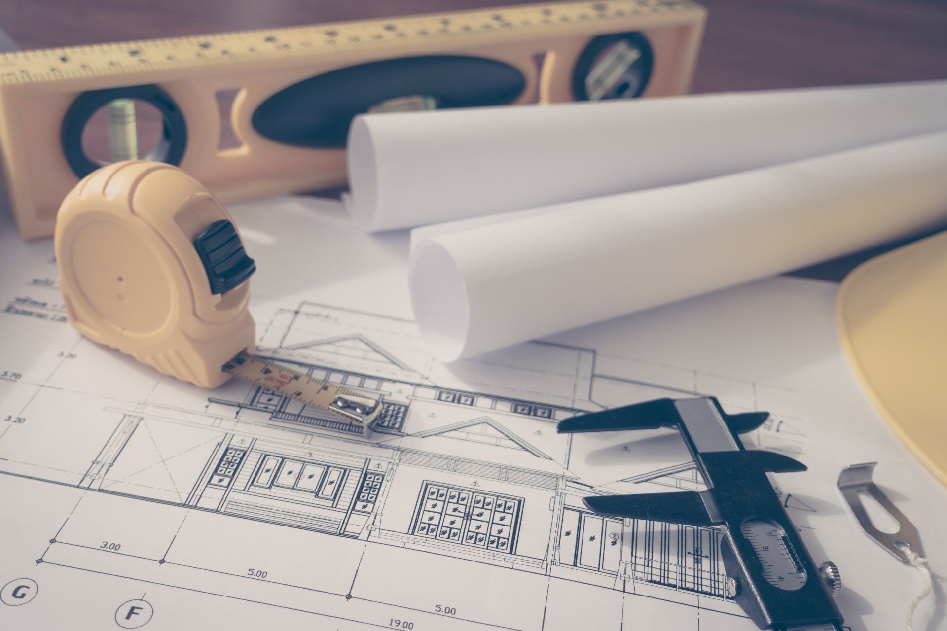 Construction plans with yellow helmet and drawing tools on blueprints
