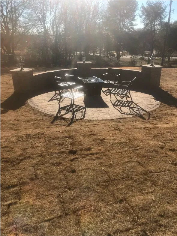 Outdoor fire pit area with metal furniture and a curved brick wall.