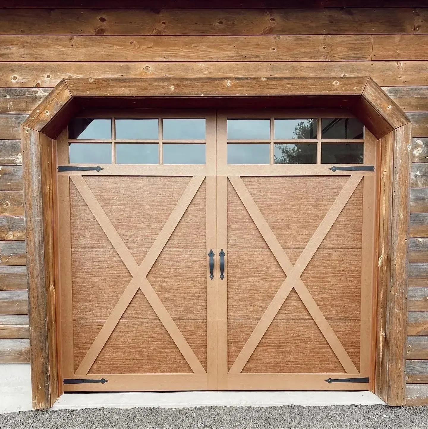 Wooden garage door with X-braced panels and small windows in a rustic log building