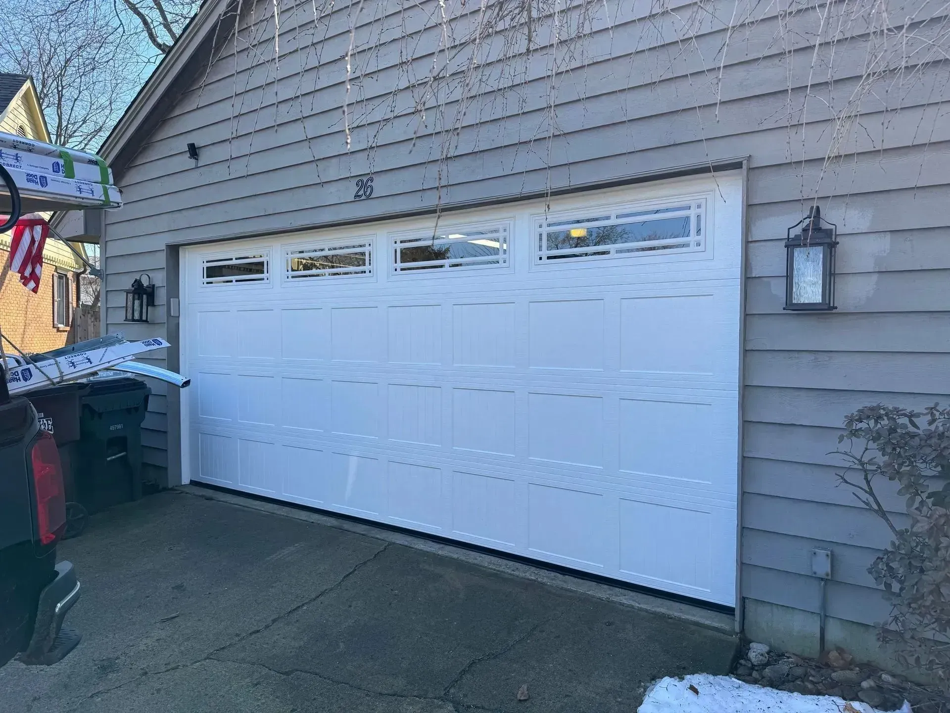 White double garage door on a gray house with driveway in front.