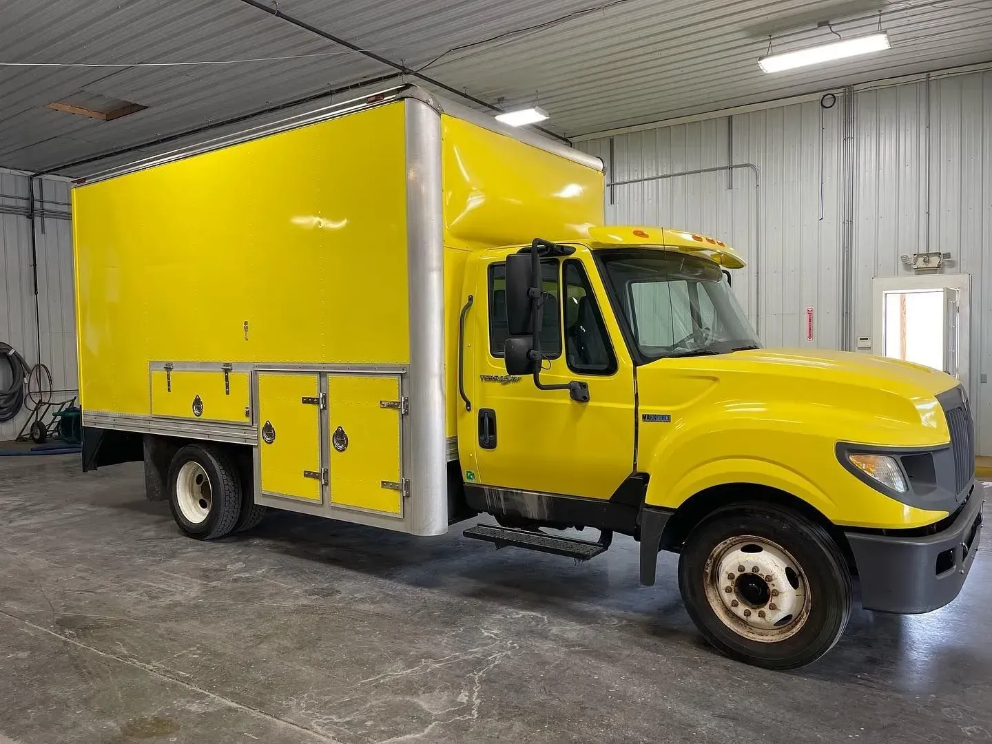 Yellow box truck parked inside a garage bay