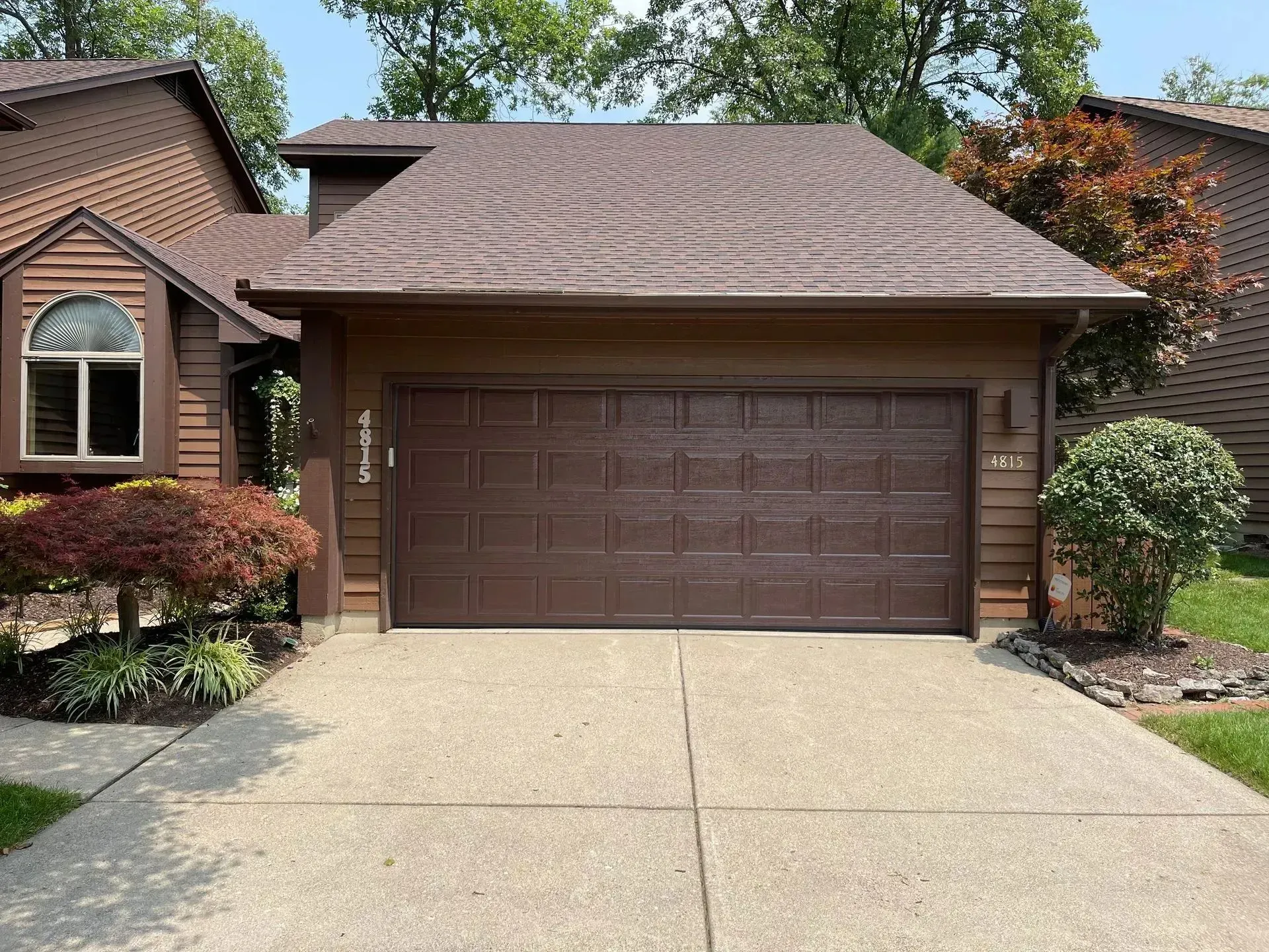Suburban house exterior with a brown garage door and concrete driveway