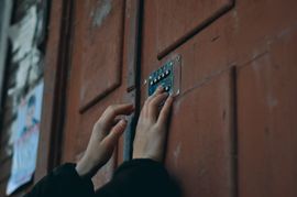 Hands entering a code on a metal door keypad