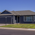 Single-story blue suburban house with a garage, front lawn, and clear sky
