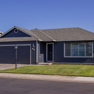 Single-story blue suburban house with a garage, front lawn, and clear sky