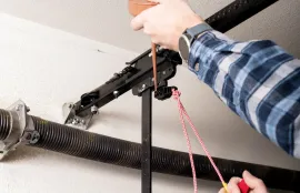 Person installing a black garage door opener rail with a red pull cord attached